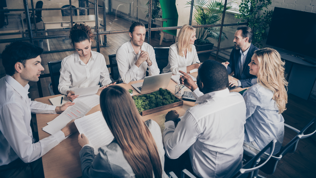 Acht Mitarbeiter an einem Tisch in einem Büro